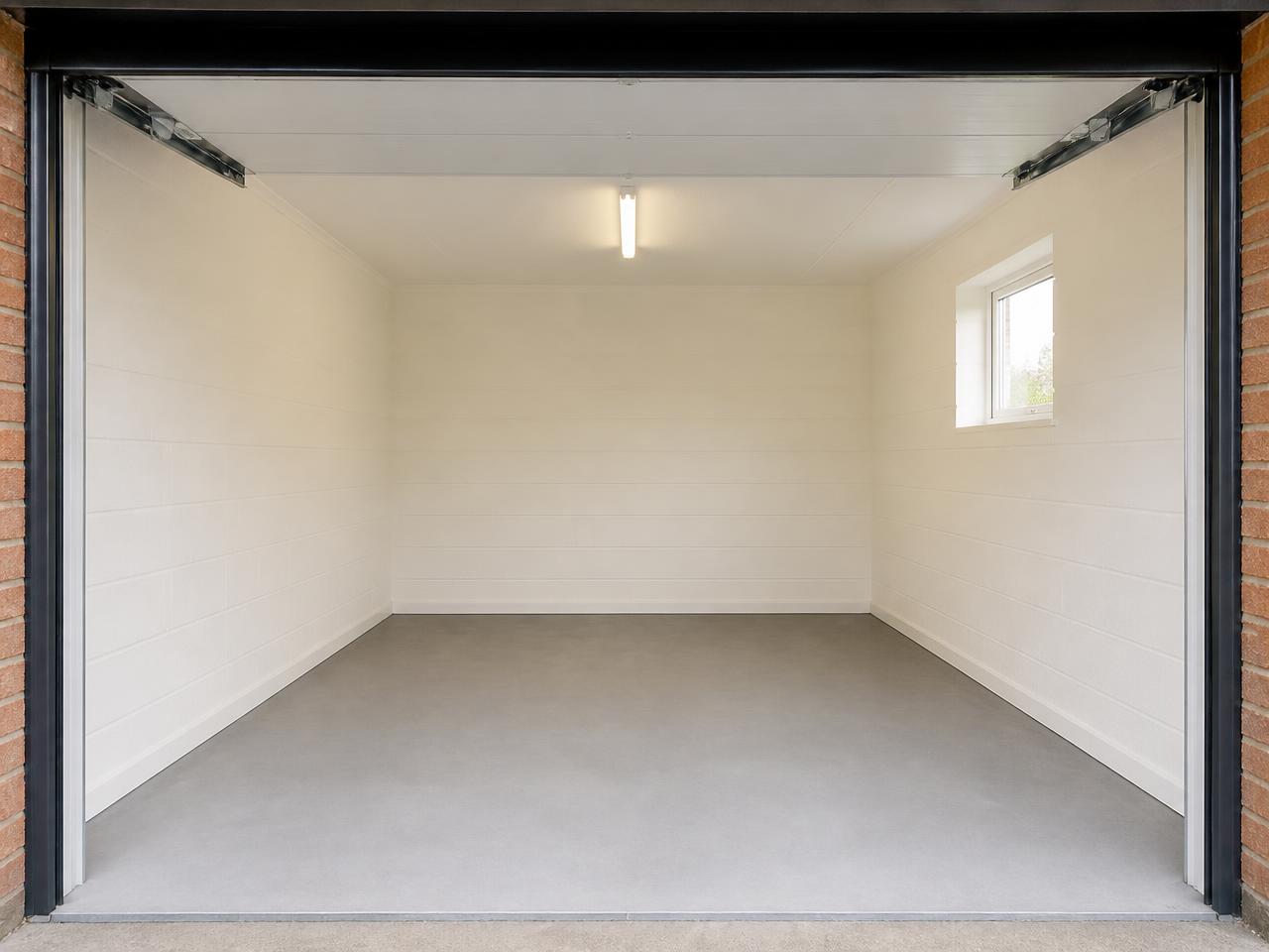 An empty, clean white single garage photographed from the open door